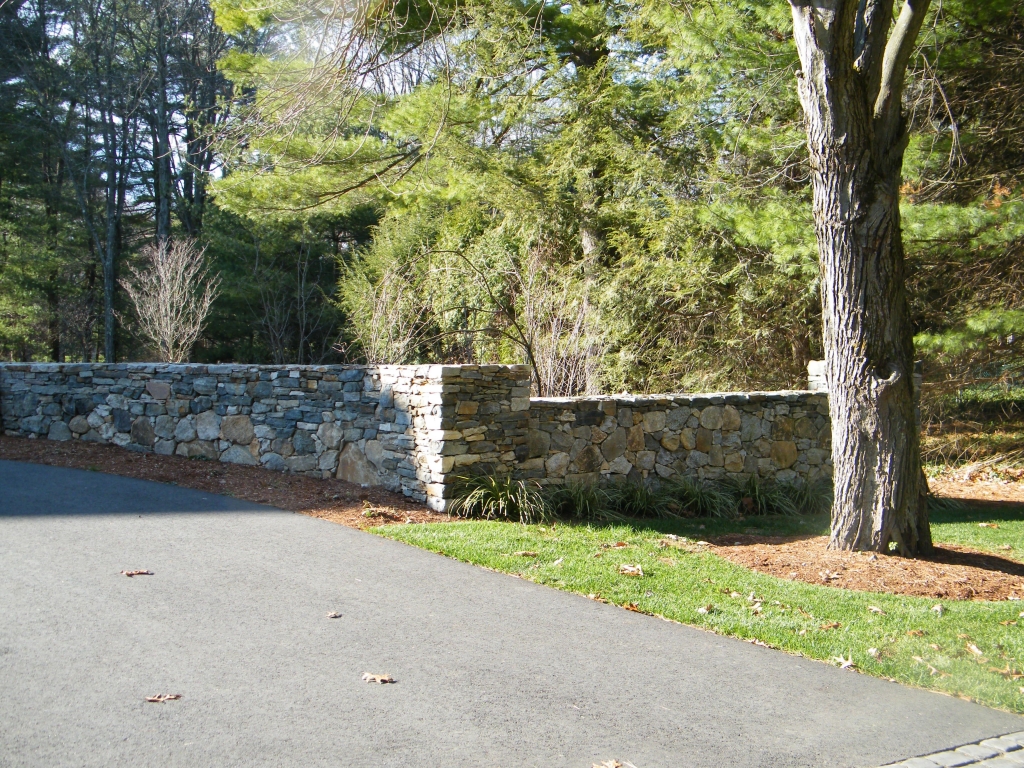 custom natural stone wall on side of driveway